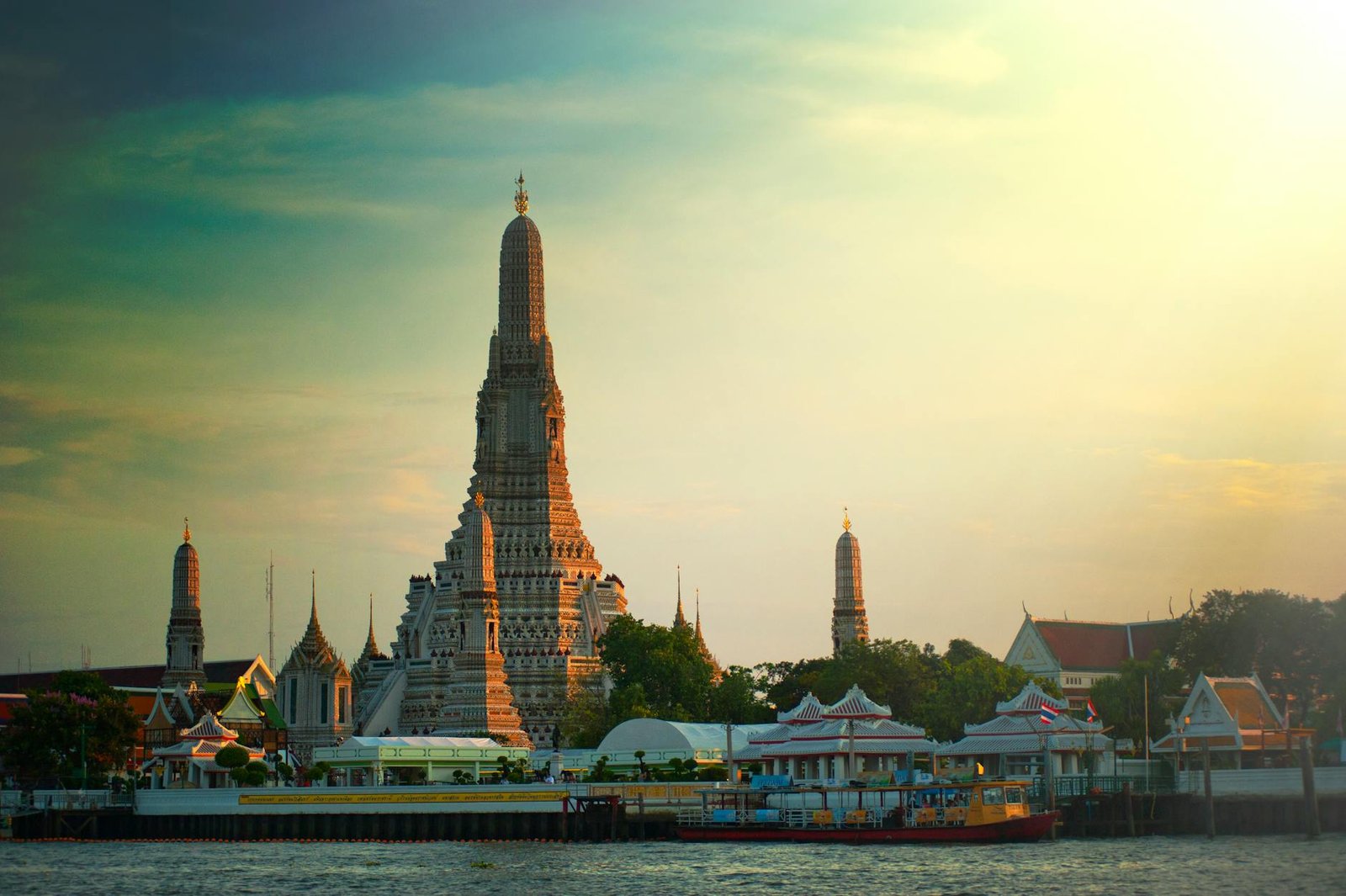 Stunning sunset view of Wat Arun temple by the Chao Phraya River in Bangkok, Thailand.