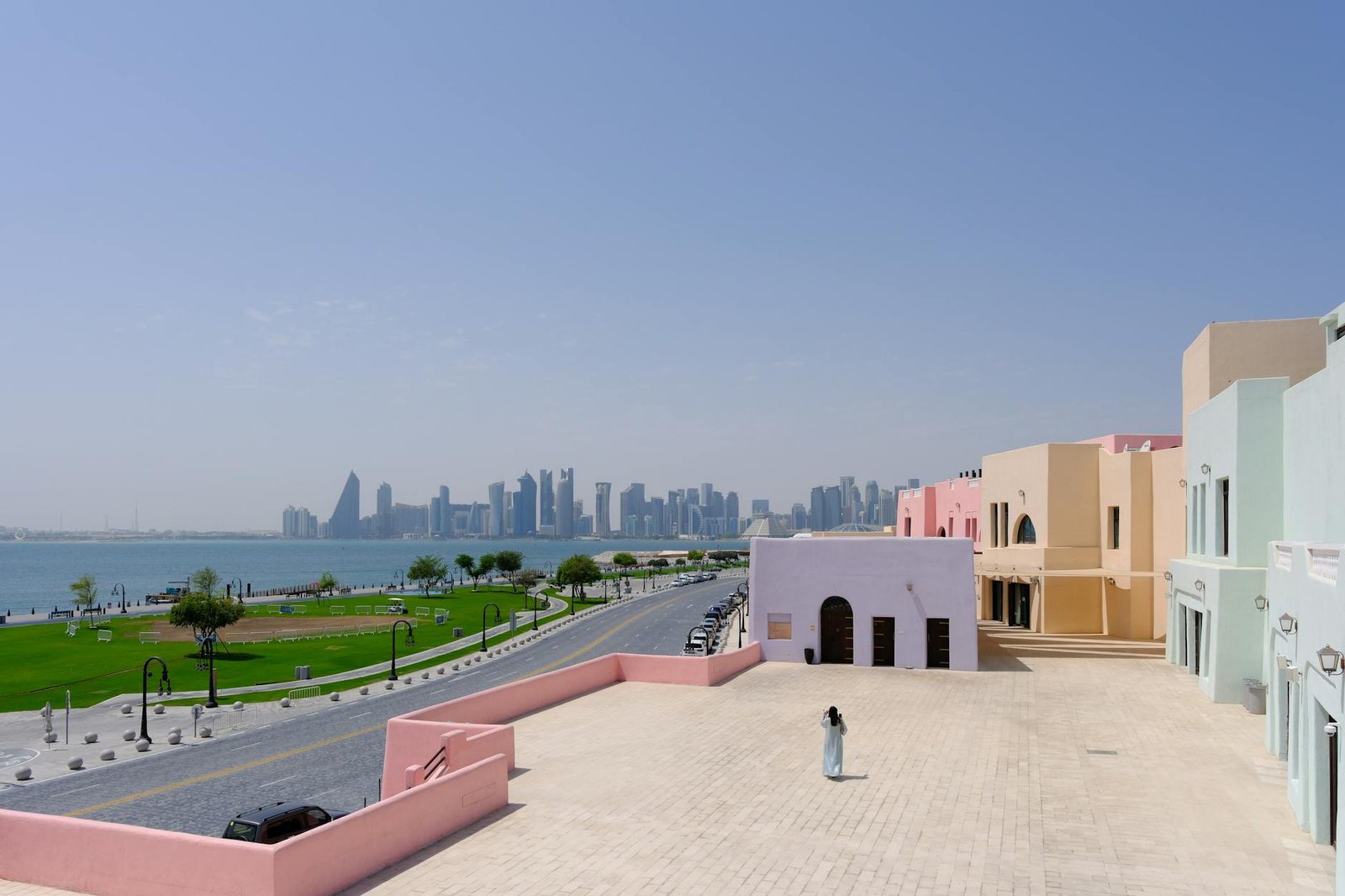 View of Doha skyline with vibrant Katara Cultural Village buildings in foreground, Qatar.