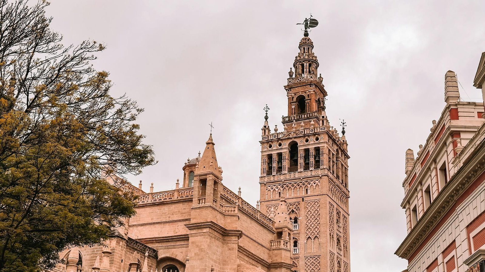 A striking view of the Giralda Tower against a cloudy sky in Sevilla, Spain.