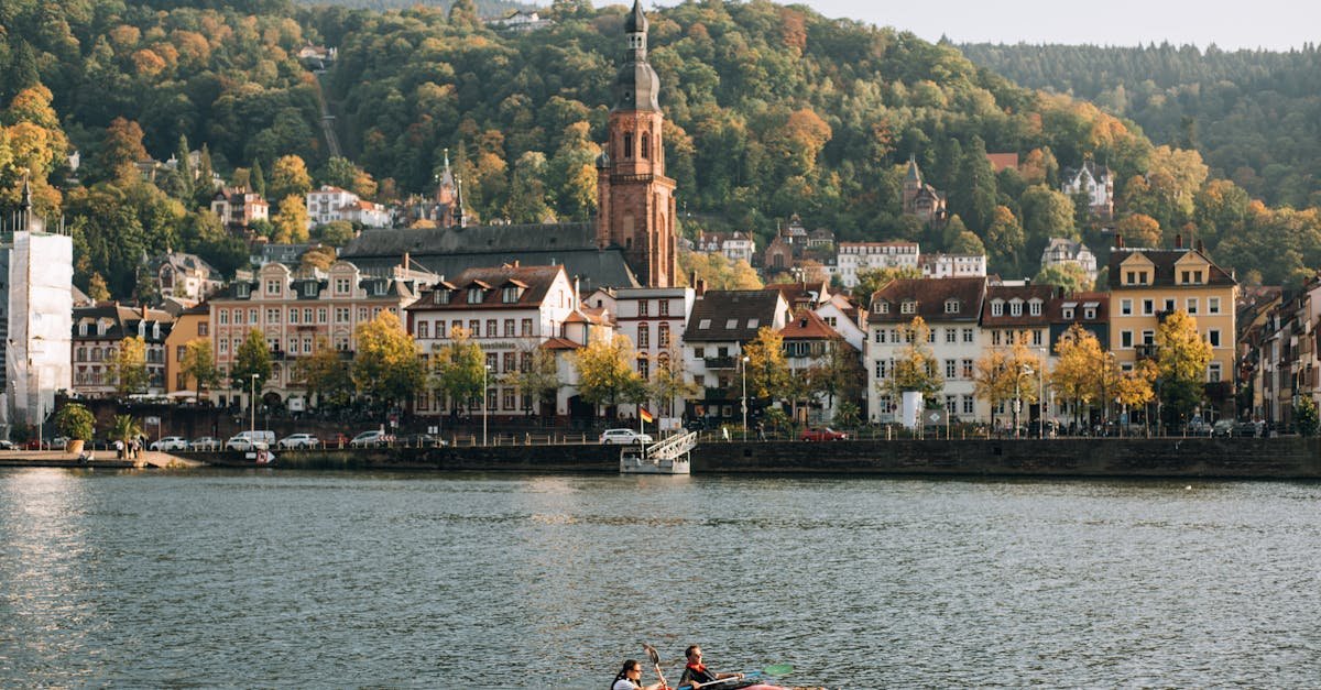 Kayakers on the Neckar River with Heidelberg's charming architecture and lush hills in the background.