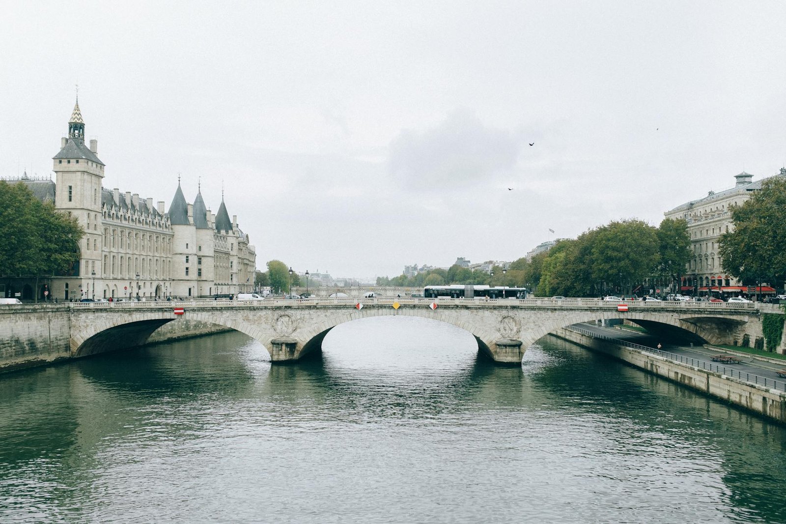 Scenic view of a historic bridge over the serene river with classic Parisian architecture in the background.